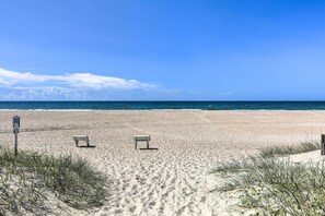 A beach with two empty chairs and a signpost. - Walk to Shore: Atlantic Beach Condo w/ Pool Access (Atlantic Beach)