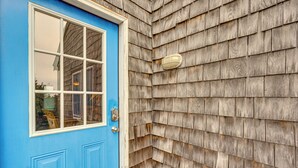 A blue door with a window and a light fixture on the exterior wall. - Rooftop Deck & Hot Tub: Outer Banks Family Getaway (Rodanthe)