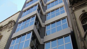 Ein modernes Gebäude mit mehreren Stockwerken, großen Fenstern und einem Eingang an der Ecke.