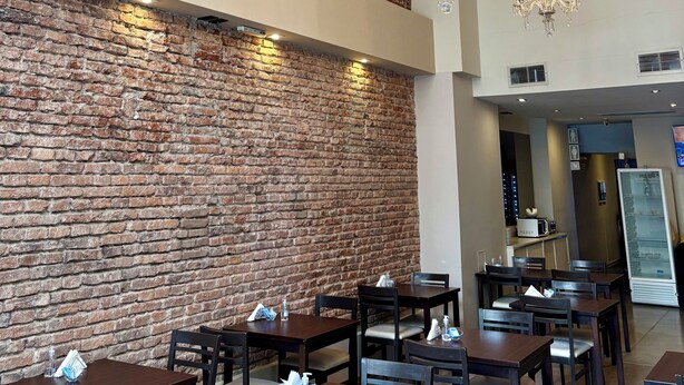 Ein Restaurant mit Ziegelwänden, Kronleuchtern und Holztischen.
