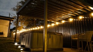 An outdoor patio area with a covered seating area, a hot tub, and a metal fence. - Spacious 4-bedroom house in Miami with Hot Tub, Lake, Kayaks, and Pool table (Miami)