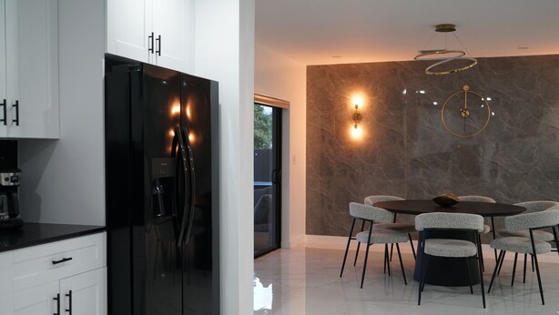 A modern kitchen with a black refrigerator, white cabinets, and a dining area with a round table and grey chairs. - Spacious 4-bedroom house in Miami with Hot Tub, Lake, Kayaks, and Pool table (Miami)