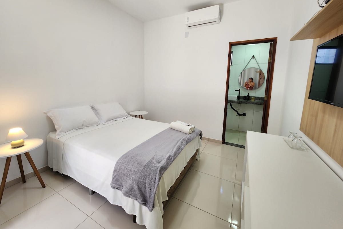 Un dormitorio moderno con cama, mesita de noche y una pequeña mesa redonda con lámpara.