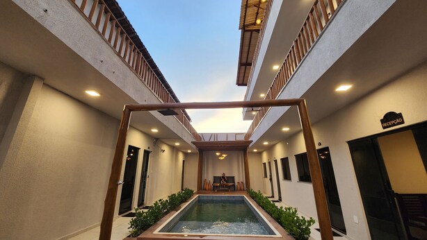Pasillo de hotel con piscina central, barandales de madera y una zona de recepción.
