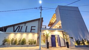 Un edificio moderno con la palabra "VILLE" en la fachada, un balcón y una entrada bien iluminada.