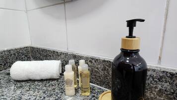 Una encimera de baño con una botella negra de jabón para manos, una toalla blanca y varias botellas de loción.
