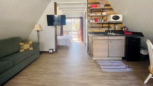 Ein kompakter Wohnbereich mit Küchenzeile, Flachbildfernseher, Deckenventilator und Sofa.