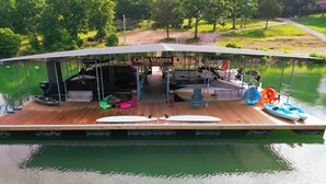 A boat with a covered deck, a sign reading "Calm Waters Cabin Resort," and various watercraft and equipment.