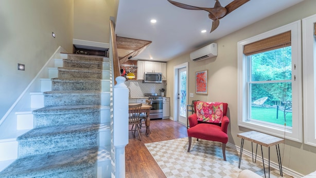 A staircase leading to a kitchen with a dining area, a red chair, and a window with a view of the outdoors. - Cozy & Quiet Retreat ~ Walk to SoCo and Town Lake! (Austin)