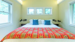 A bedroom with a bed, three windows, and a patterned bedspread. - Cozy & Quiet Retreat ~ Walk to SoCo and Town Lake! (Austin)