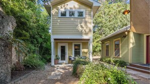 A two-story house with a front porch, a small garden, and a pathway leading to the entrance. - Cozy & Quiet Retreat ~ Walk to SoCo and Town Lake! (Austin)