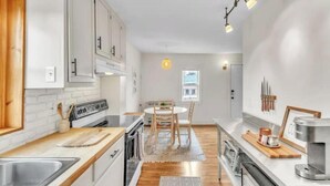 A modern kitchen with white cabinets, wooden countertops, and a central island with seating.