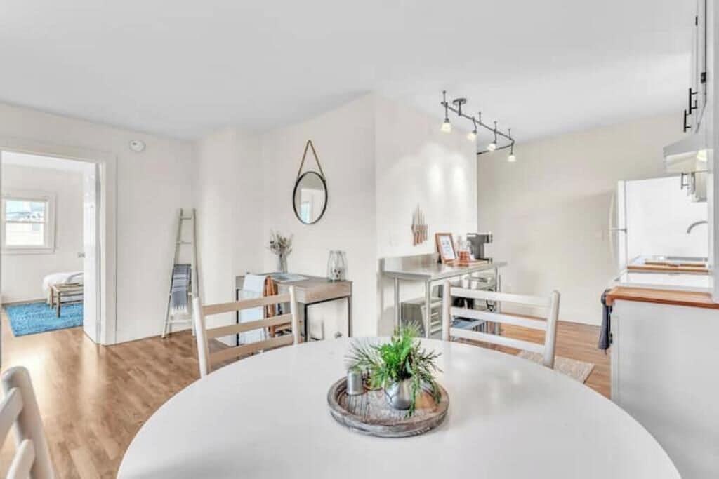 A modern, well-lit dining area with a round table, white chairs, and a decorative centerpiece.