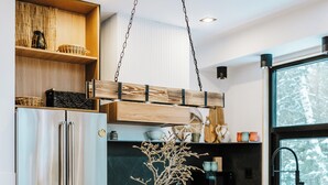 Et moderne køkken med en central ø, rustfrie stålapparater og sorte barstole.