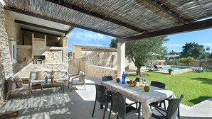 An outdoor patio with a table set for dining, surrounded by stone walls and a pool in the background. - VILLA VINYA FRARES - LUXURY RETREAT (Pollensa)
