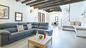 A modern living room with a grey sectional sofa, a wooden coffee table, and a staircase leading to another level. - VILLA VINYA FRARES - LUXURY RETREAT (Pollensa)
