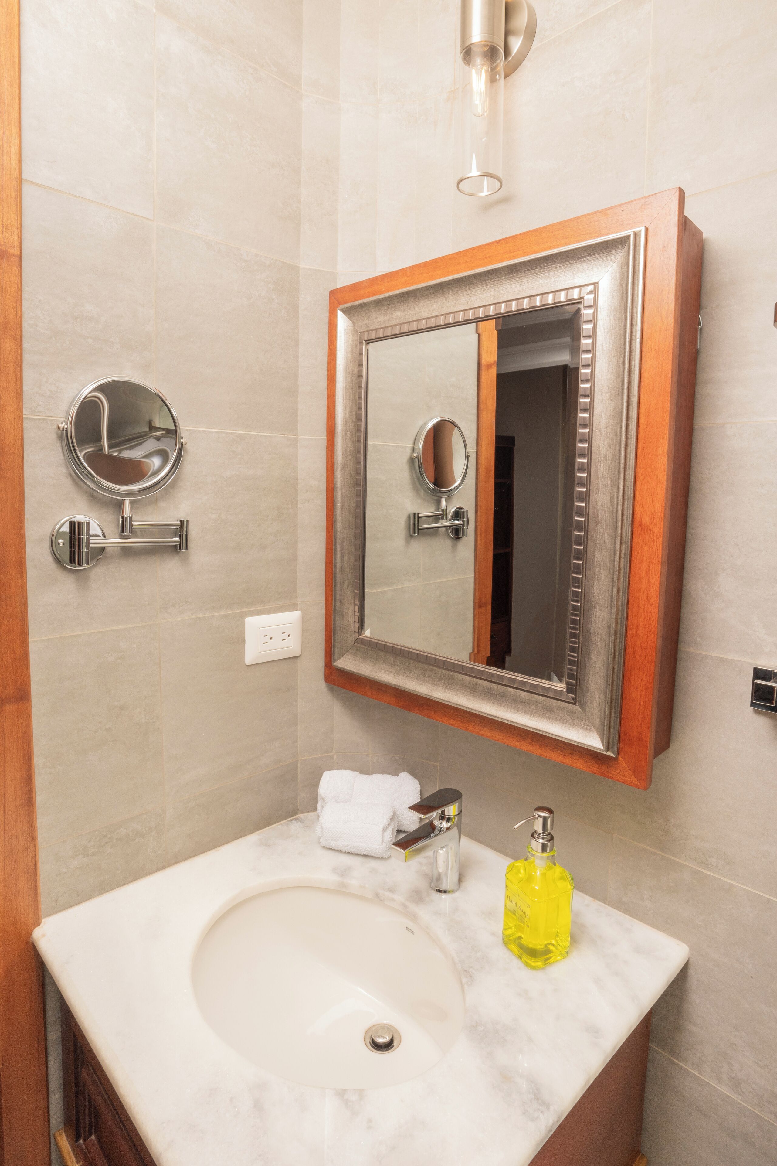 A bathroom with a marble sink, a mirror with a wooden frame, and a towel on the counter.
