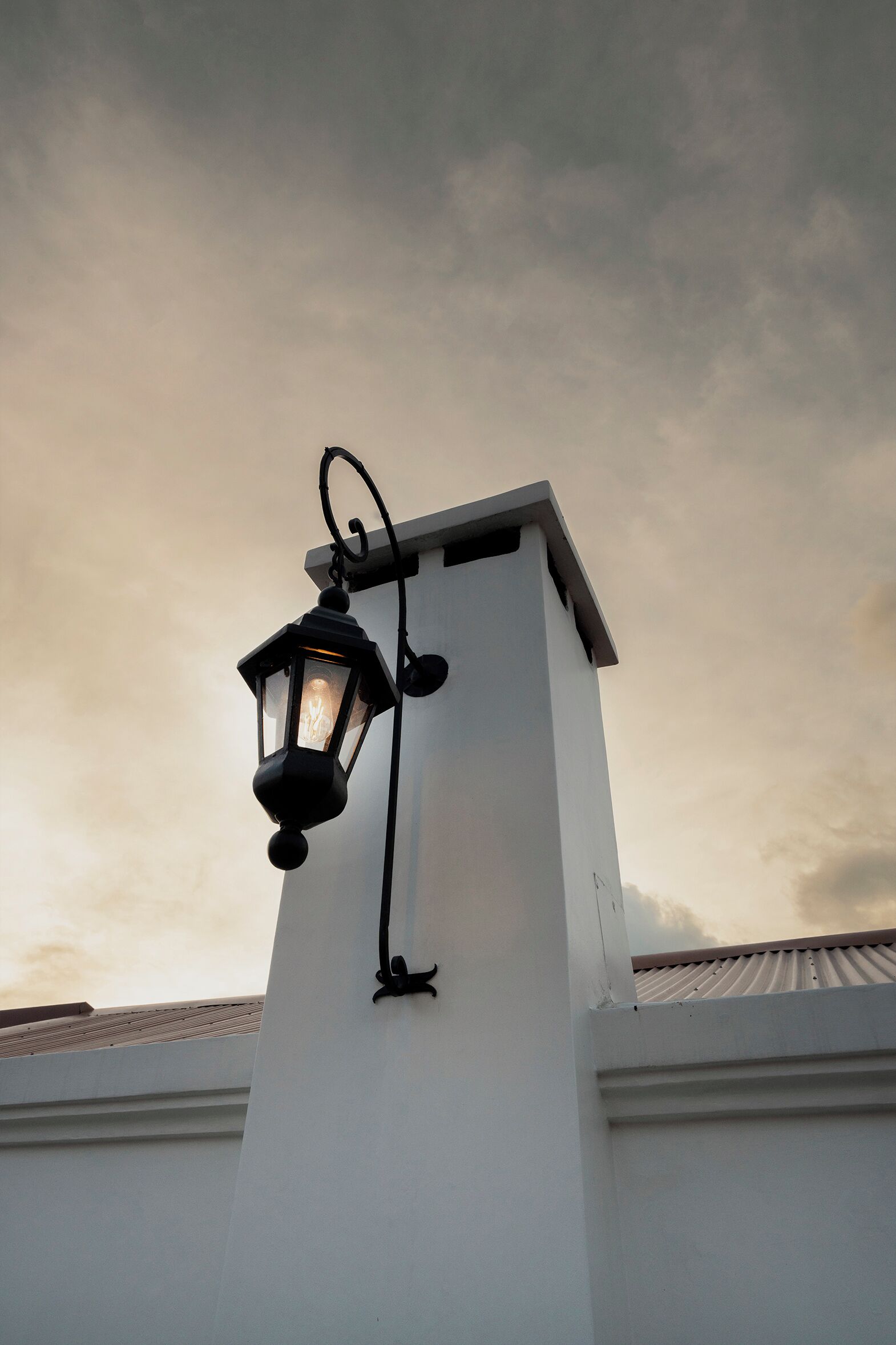 Un bâtiment blanc avec une lanterne noire fixée à l’angle.