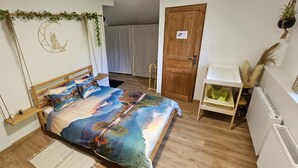 A bedroom with a bed, a wooden door, a small shelf, and a radiator. - Summer/winter rental, ski - hiking Haute-Savoie - peaceful location - friends/family (La Rivière-Enverse)