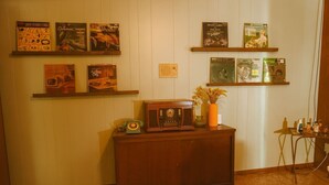 A room with a wooden cabinet, a vintage radio, and several framed items on shelves. - 1960's Time Capsule, in Alvin, Tx (Alvin)