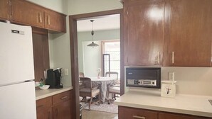 A kitchen with wooden cabinets, a refrigerator, a microwave, and a coffee maker. - 1960's Time Capsule, in Alvin, Tx (Alvin)