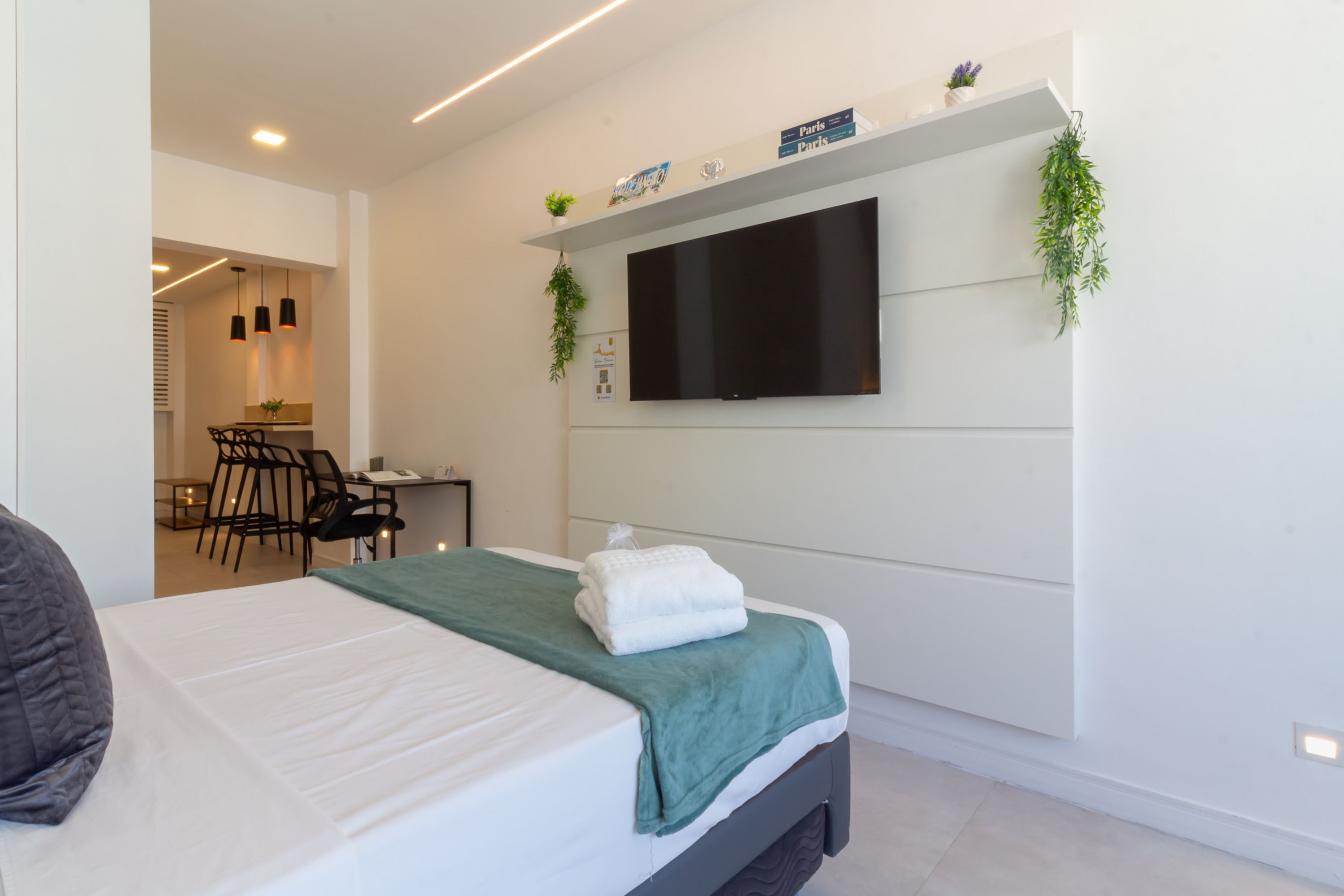 Ein modernes Hotelzimmer mit Bett, Schreibtisch und einem an der Wand befestigten Flachbildfernseher.