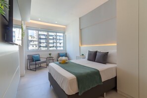 A modern bedroom with a large bed, bedside tables, a window with a city view, and a flat-screen TV mounted on the wall. - Cosy in Copacabana for Two Pj909 (Rio de Janeiro)