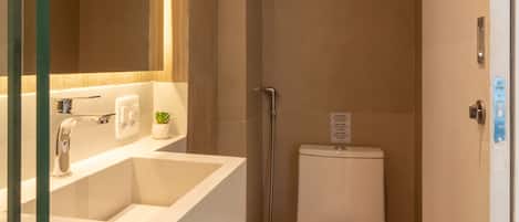 Un baño moderno con lavamanos, espejo y retrete blancos.