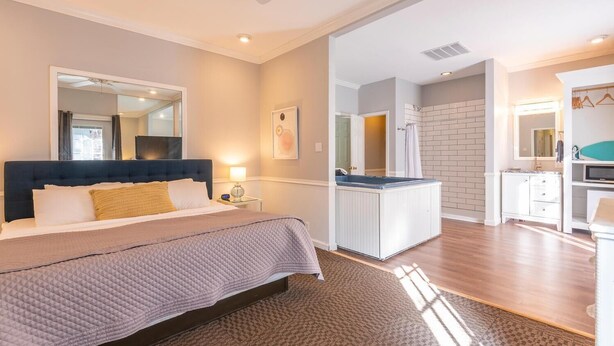 Een moderne hotelkamer met een groot bed, een kleine badkamer met douche, en een kitchenette.