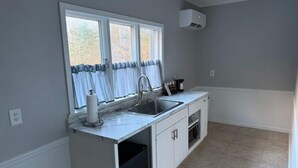 A kitchen with a window, a sink, a dishwasher, and a microwave. - Luxury Hot tub Suite w/ In-Room Hot Tub & King Bed 1BR, 1BA (Nashville)