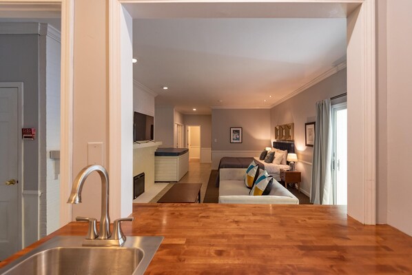 A modern kitchen with a stainless steel sink and wooden countertop, leading to a living area with a sofa and a coffee table. - Luxury Hot tub Suite w/ In-Room Hot Tub & King Bed 1BR, 1BA (Nashville)