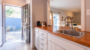 A modern kitchen with a wooden countertop, stainless steel sink, and white cabinetry. - Luxury Hot tub Suite w/ In-Room Hot Tub & King Bed 1BR, 1BA (Nashville)