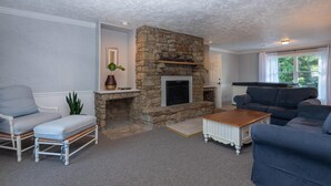 A living room with a stone fireplace, a grey sofa, a blue sofa, and a wooden coffee table. - Luxury Hot tub Suite w/ In-Room Hot Tub & King Bed 1BR, 1BA (Nashville)