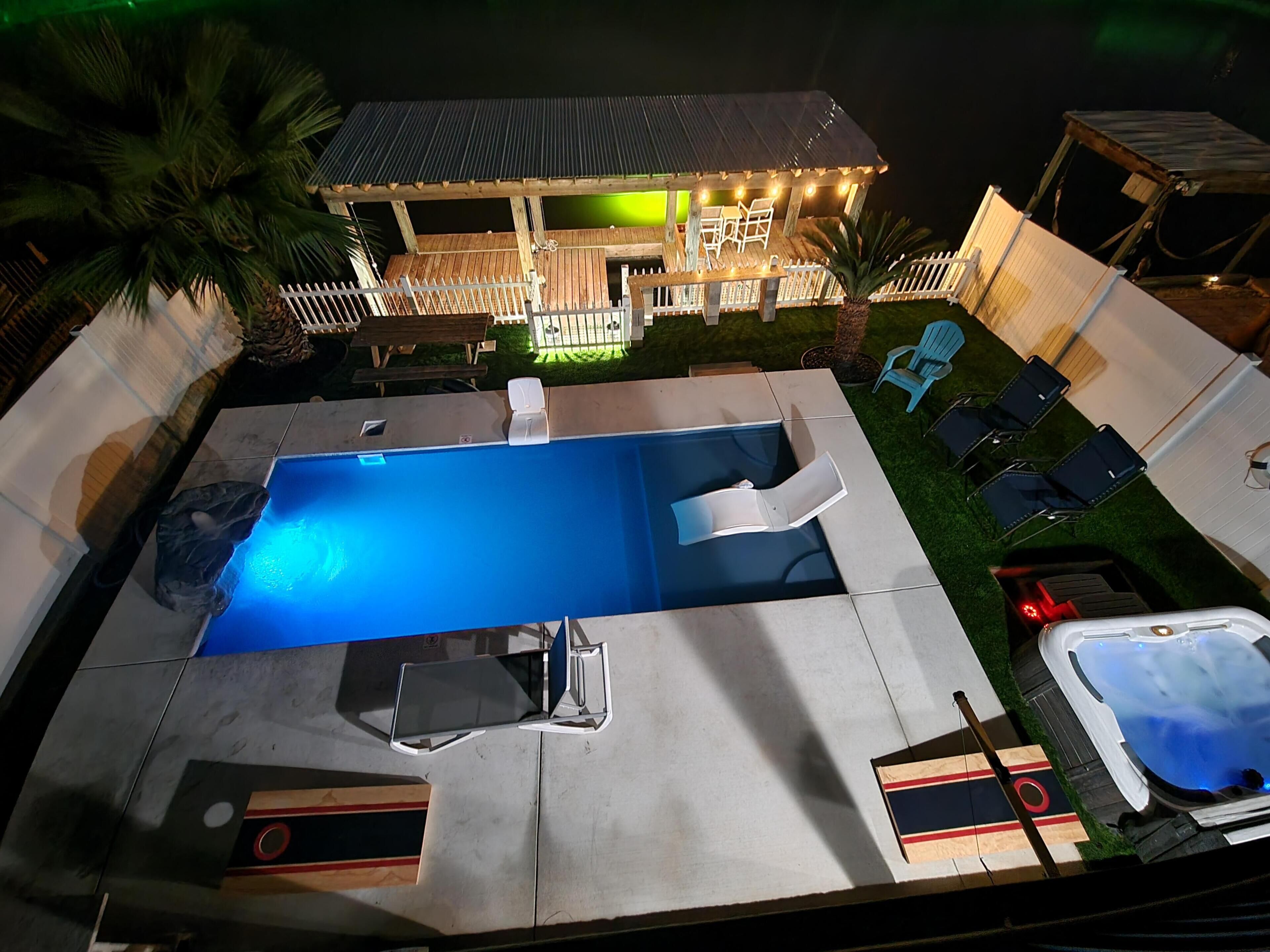 A swimming pool with lounge chairs, a hot tub, and a deck area with a railing.