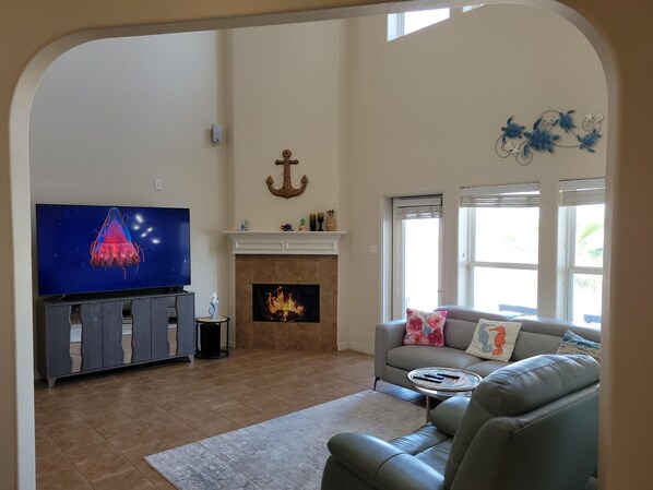 A living room with a fireplace, a television, and a sofa. - Island Waterfront 3/2 Private Pool & Hot Tub with Boat Dock (Corpus Christi)