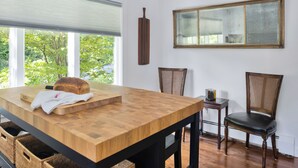 A dining area with a wooden table, chairs, and a view of greenery outside. - Charming Home with Fireplace and Indoor Pool in Sharon, CT (Sharon)