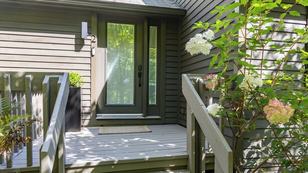 A house with a front porch, a door, and a small garden area with plants. - Charming Home with Fireplace and Indoor Pool in Sharon, CT (Sharon)