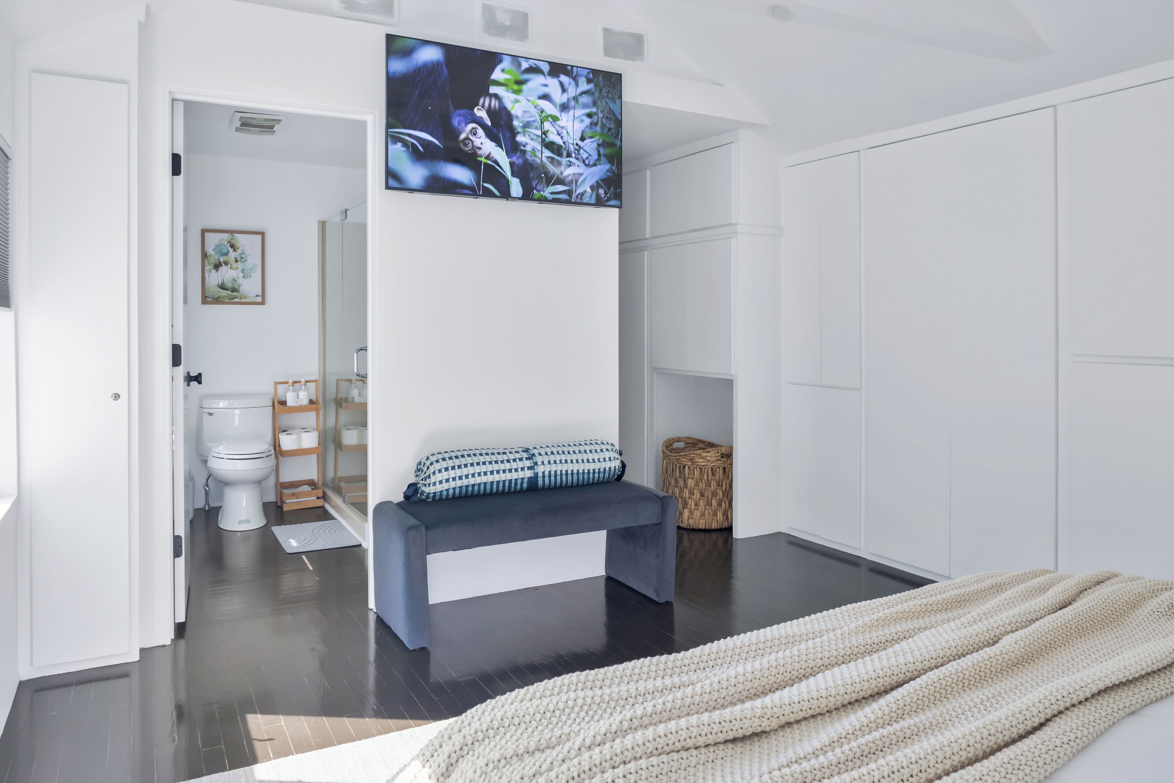 Une salle de bain moderne avec un banc, un grand miroir et un téléviseur fixé au mur.