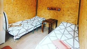 A small room with two beds, a wooden table, and a hanging rack. - Camping Three poplars by VL (Alaverdi)