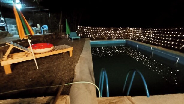 A swimming pool with a wooden deck and a slide, surrounded by decorative lights. - Camping Three poplars by VL (Alaverdi)