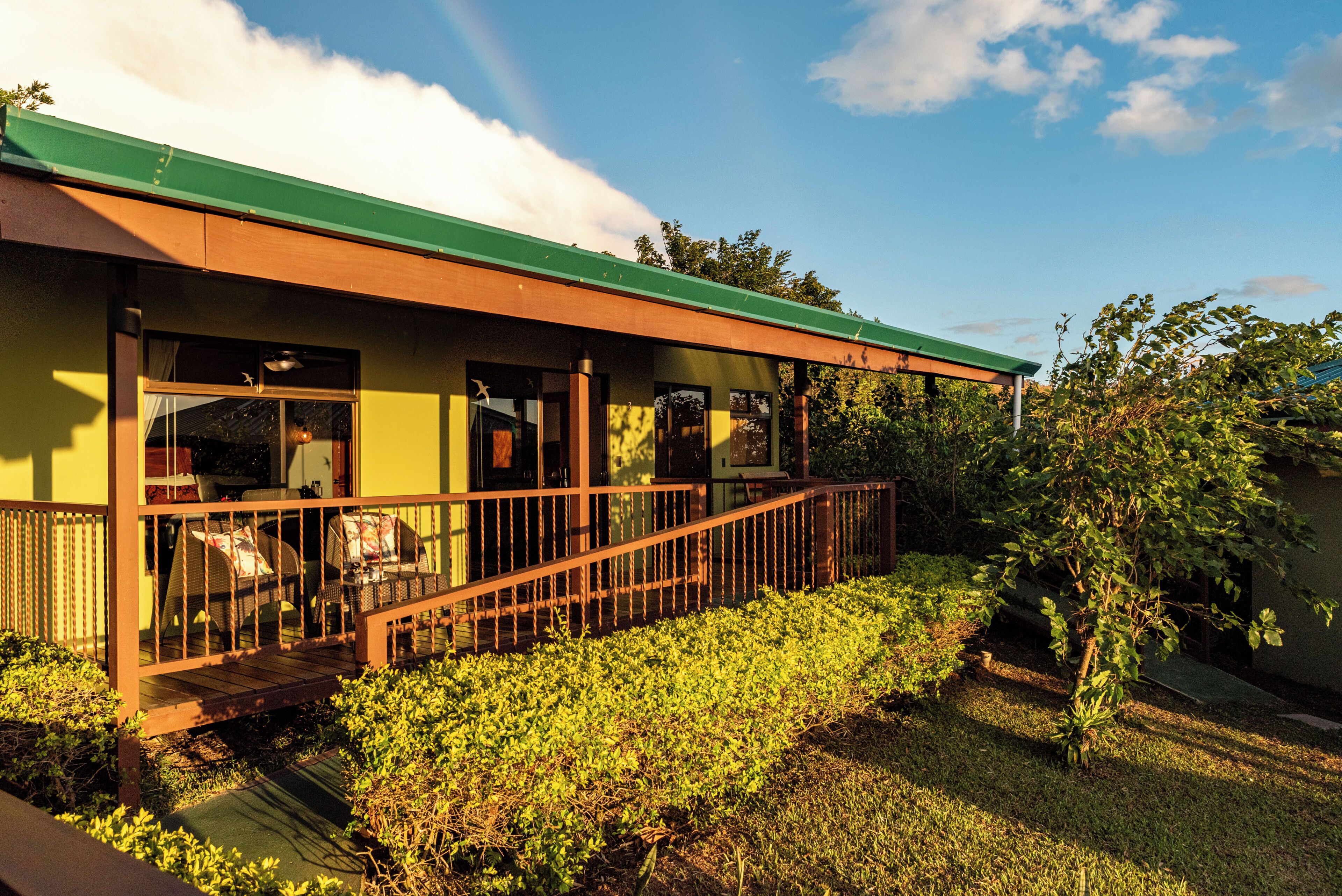 A house with a porch, a green roof, and a garden.