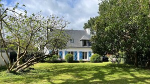 A house with a well-maintained lawn, a large tree, and a clear sky. - Two houses in a beautiful garden in Carnac, ideal for 2-3 families with children (Carnac)