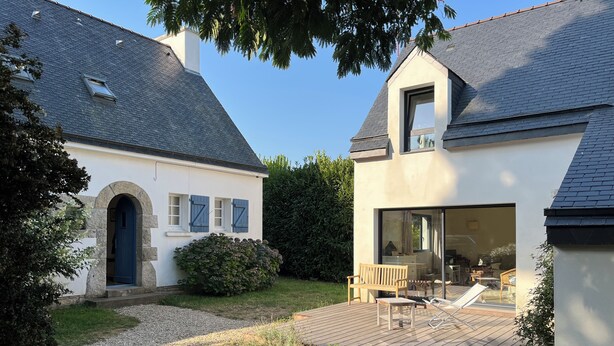 A two-story house with a patio area featuring outdoor furniture. - Two houses in a beautiful garden in Carnac, ideal for 2-3 families with children (Carnac)