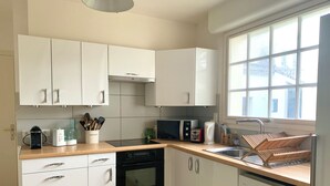 A modern kitchen with white cabinets, a Bosch dishwasher, a microwave, and a sink. - Two houses in a beautiful garden in Carnac, ideal for 2-3 families with children (Carnac)
