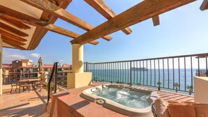Un balcon avec un jacuzzi, du mobilier d’extérieur et une vue sur la mer.