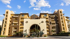 Un hôtel à plusieurs étages, doté d’une arche centrale, de balcons et d’une cour intérieure agrémentée de cactus et de palmiers.