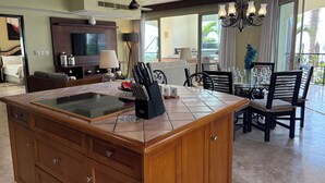 Une cuisine spacieuse avec un grand îlot central, un coin repas avec des chaises et un balcon offrant une vue agréable.