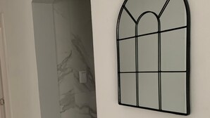 Un pasillo con pared de mármol y ventana de marco negro.