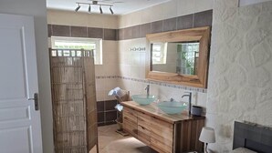 Une salle de bain moderne avec un meuble-lavabo en bois, un vasque en verre et un grand miroir.
