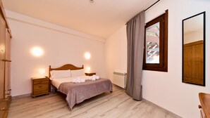 Een slaapkamer met een houten bed, nachtkastjes, een radiator en een raam met gordijnen.